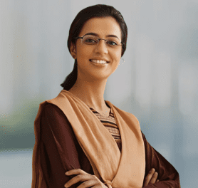 A woman with glasses and a necklace is smiling.