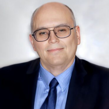 A man in a suit and tie wearing glasses.